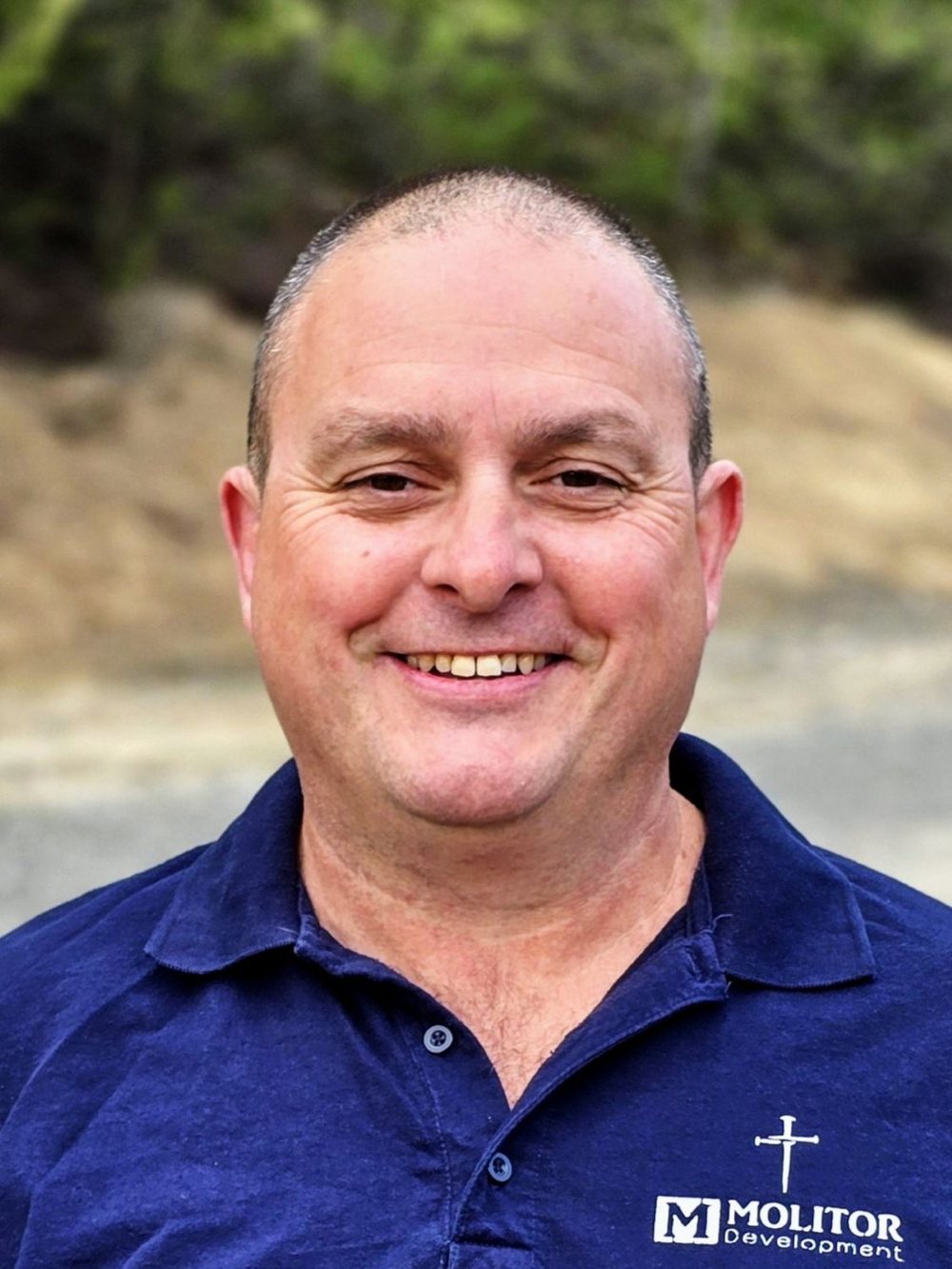 Headshot of Rick smiling outdoors in a navy Molitor Development polo shirt.