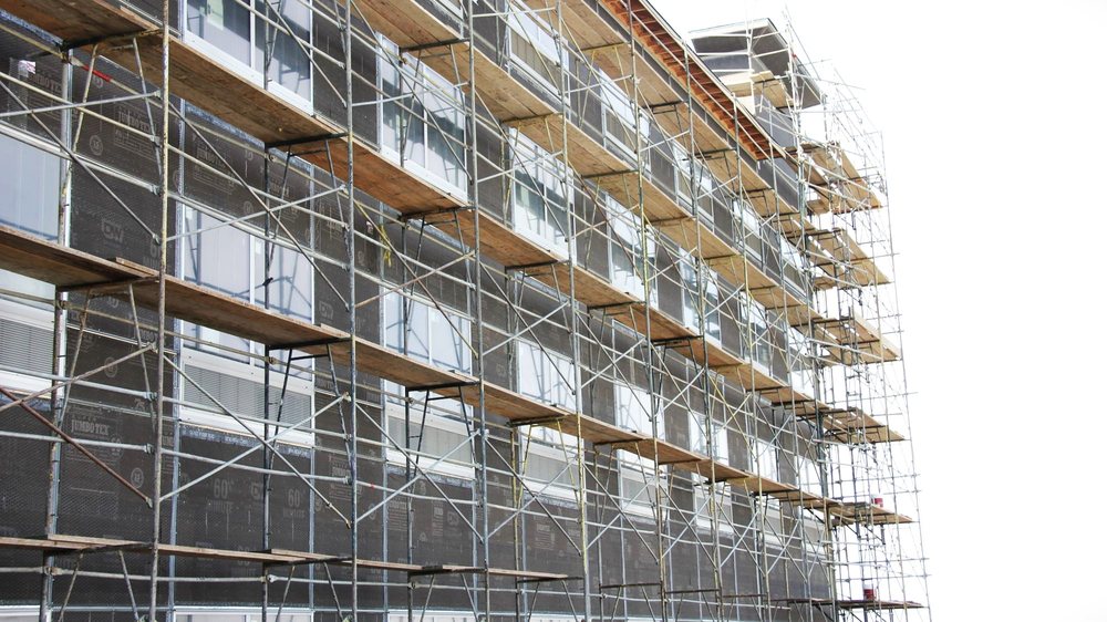 Apartment building exterior under renovation with scaffolding installed across the facade.