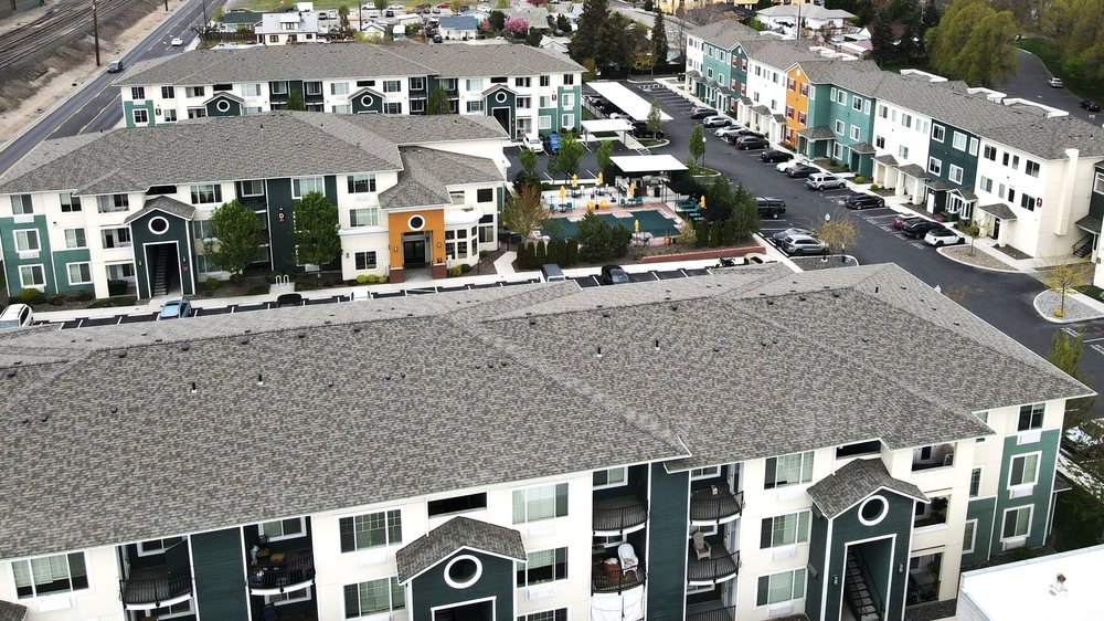 Aerial view of an apartment community with a central swimming pool, courtyard, and surrounding buildings.