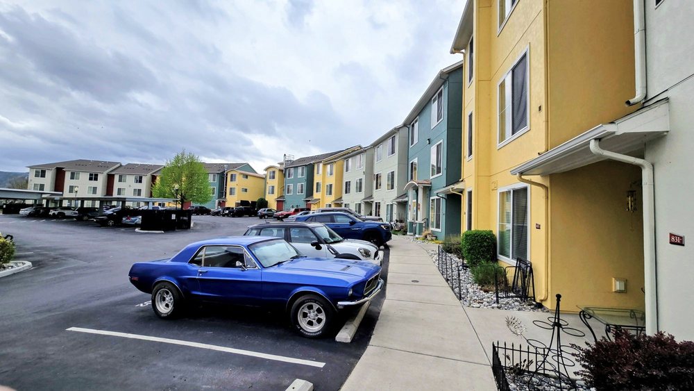Colorful apartment buildings beside a parking area with a blue classic car in the foreground.
