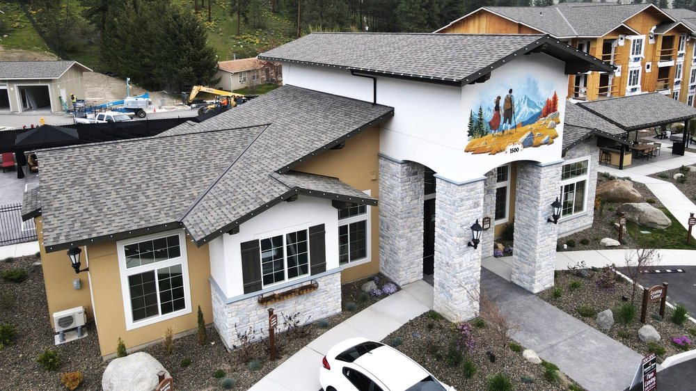 Apartment community leasing center with stone columns, landscaped grounds, and a mountain-themed mural.