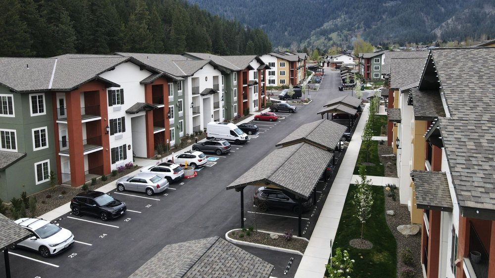 Aerial view of a mountain apartment community with colorful buildings, parking areas, and covered carports.