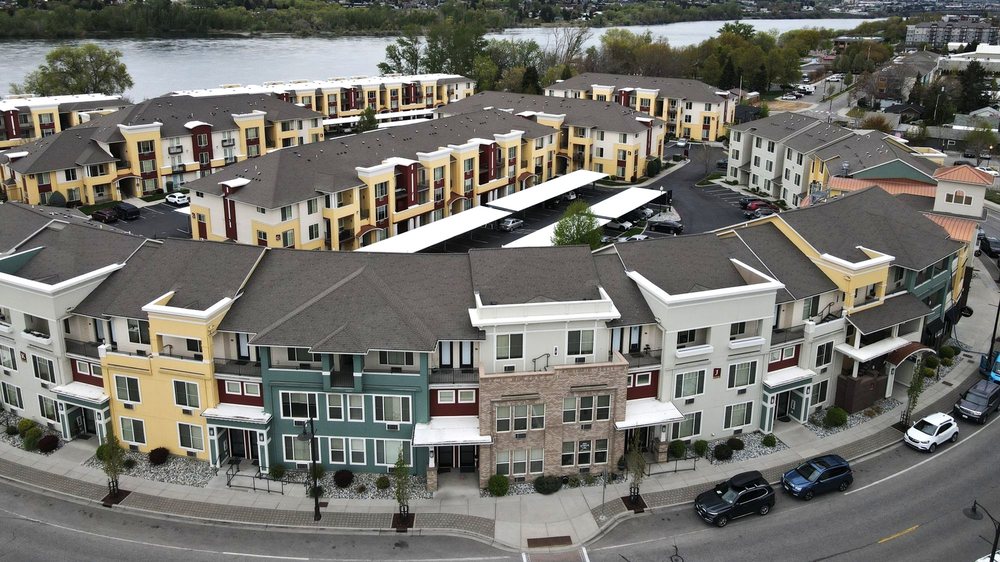 Aerial view of a Riverside apartment community with colorful buildings near a wide river.