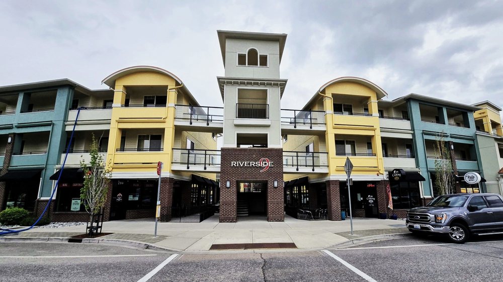 Street-level view of a Riverside mixed-use apartment building with storefronts and a central entrance.